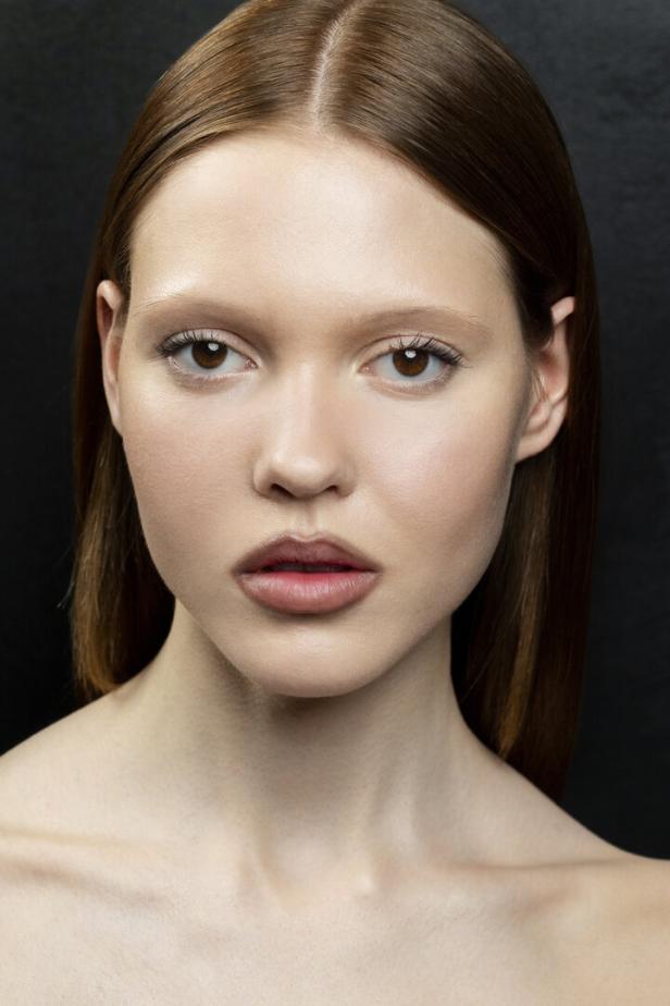 Das Close-up unseres Beauty-Trendlooks rückt die im Stil von Nina Park geschminkten Lippen in den Fokus. Die Kontur ist sanft überzeichnet und verleiht mehr Volumen, ohne übertrieben künstlich zu wirken. Der Teint erscheint nahezu ungeschminkt, mit natürlicher Hautstruktur und zartem Glow.