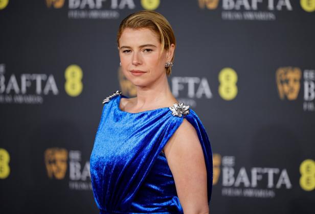  Jessie Buckley in einem blauen Kleid und vollen Lippen.