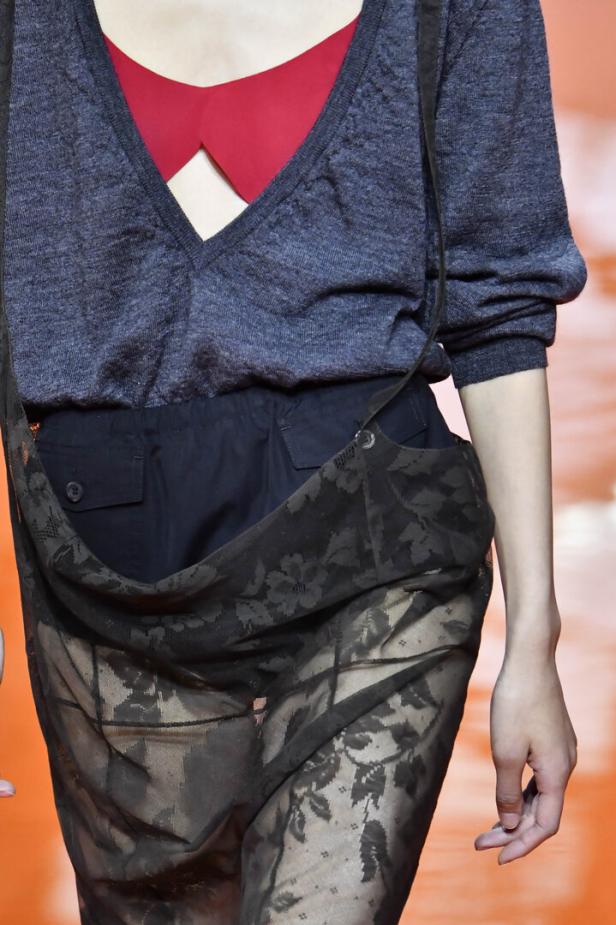 Eine Frau mit einem roten BH, und einer blauen offenen Bluse und einem schwarzen Spitzentuch um die Hüfte