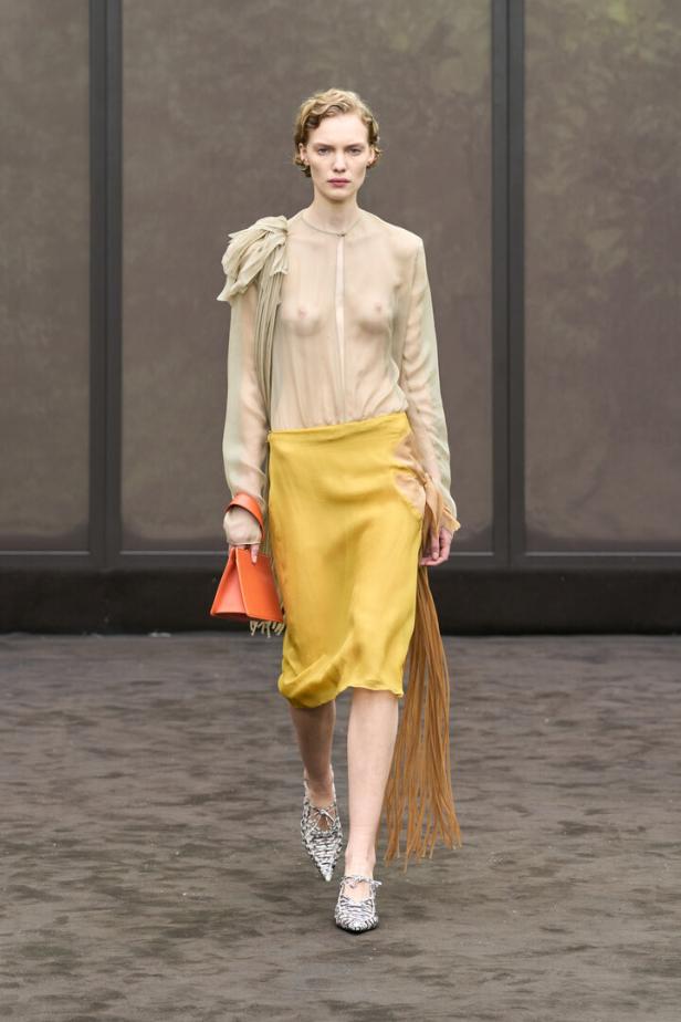 Eine Frau im Gelben Rock und mit durchsichtigem gelben Oberteil