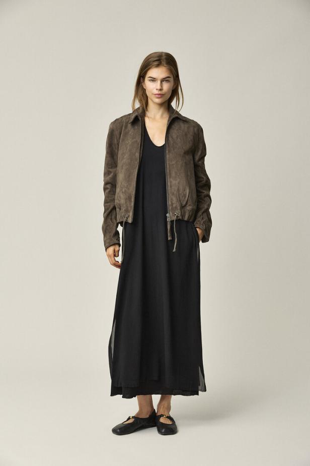 Frau in schwarzem Kleid mit brauner Jacke