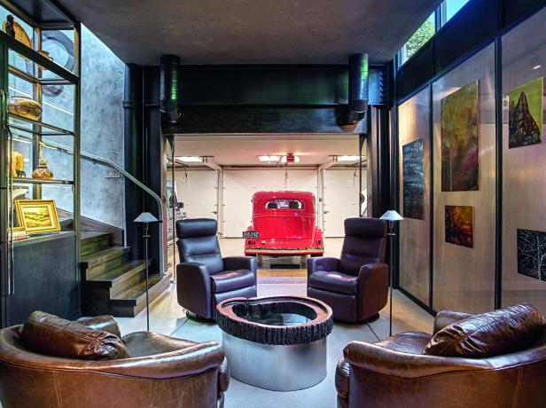 Vier braune Ledersessel stehen um einen modernen Tisch, im Hintergrund ist ein rotes Oldtimer-Auto in einer Garage zu sehen.