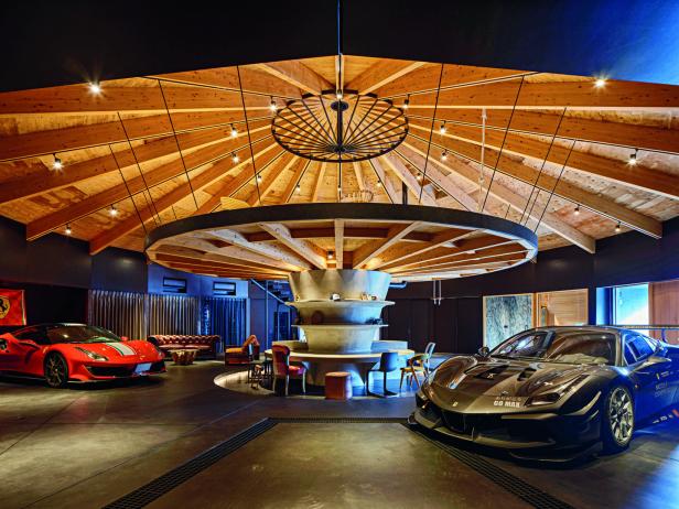 Zwei Sportwagen stehen in einer luxuriösen Garage mit auffälliger Holzdecke und modernem Loungebereich.