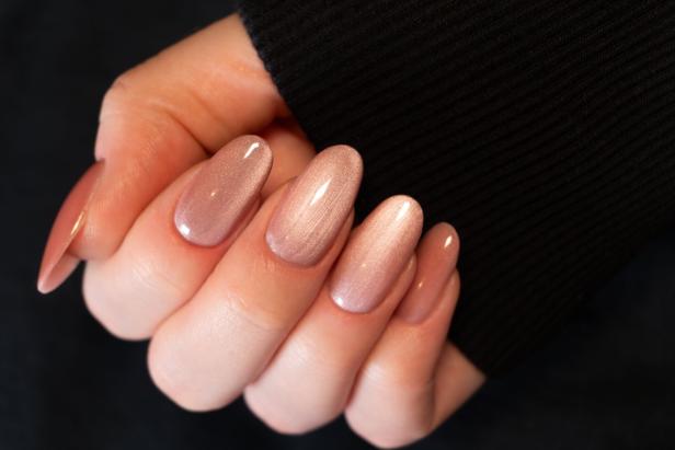 Eine Hand mit langen, mandelförmigen Fingernägeln in schimmerndem Roséton und glänzendem Finish im Cat Eye Look.