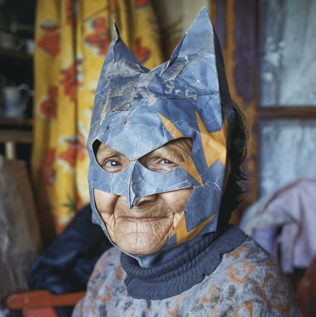 Eine ältere Person trägt eine selbstgebastelte, blaue Maske mit gelben Blitzen und spitzen Ohren.