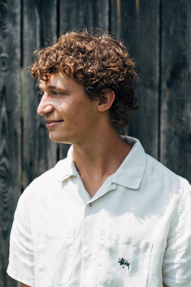 Ein Mann mit weißem Polo und blonden Locken