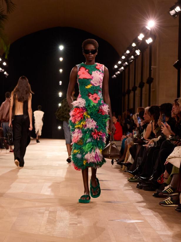 Eine Frau am Laufsteg mit einem flauschigen Kleid voller Blumen