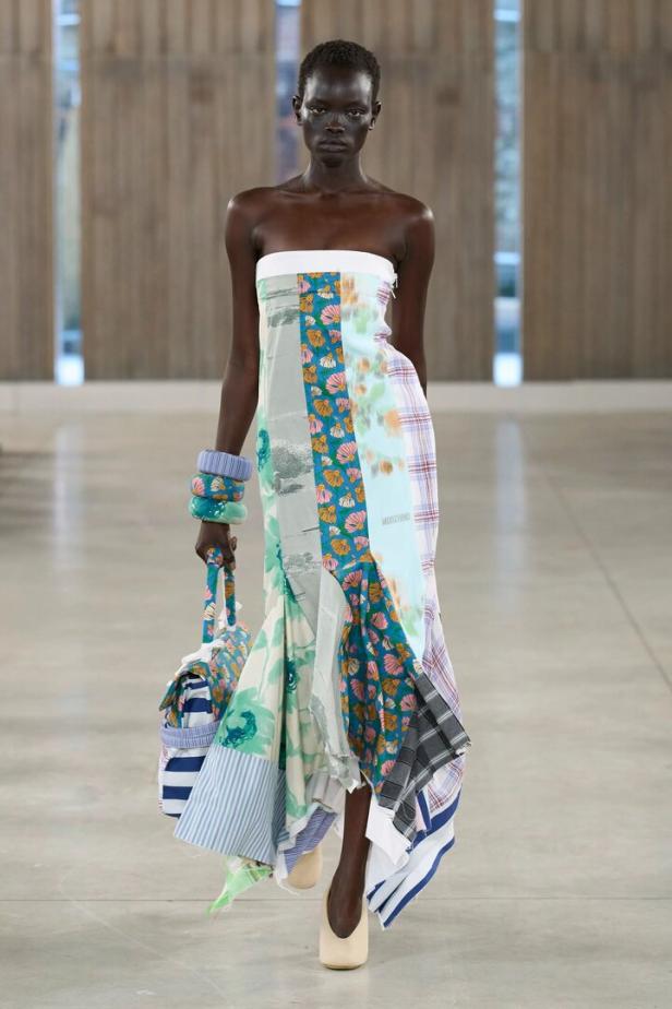 Frau in wallendem Kleid am Laufsteg mit vielen Mustern