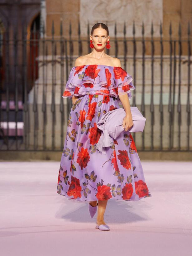 Frau in Lila Kleid mit lila Tasche mit Roten Blumen auf dem Kleid