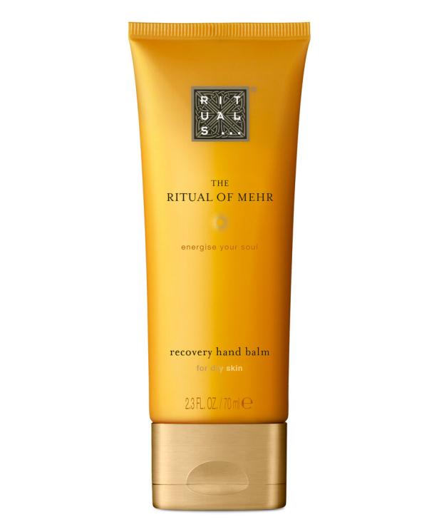 Eine goldfarbene Tube "The Ritual of Mehr" Handbalsam für trockene Haut steht vor einem weißen Hintergrund.