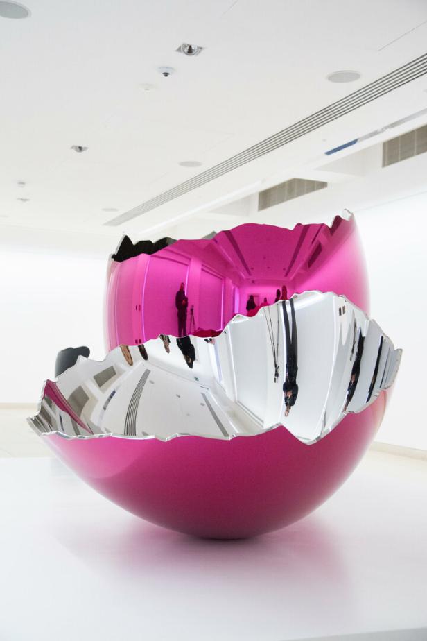 Zweiteilige, glänzende Skulptur in Pink und Silber, die wie eine aufgebrochene Eierschale aussieht.