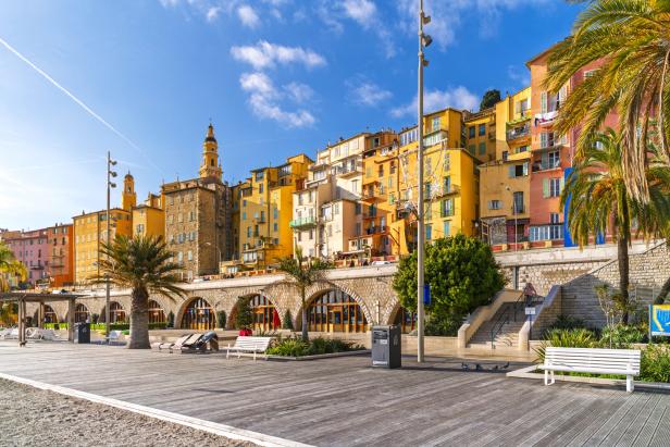 The colorful skyline including the Basilica Saint-Michael above Plage des Sablettes beach and promenade in the colorful seaside town of Menton, French Riviera.