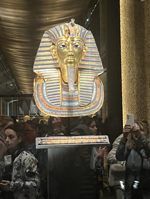Die goldene Totenmaske des Tutanchamun wird von Besuchern in einem Museum betrachtet.
