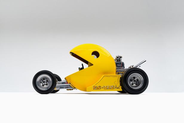 Gelbes Auto in Form der Pac-Man-Figur mit sichtbarem Motor und der Aufschrift „Pac-Man Rod“ an der Seite.