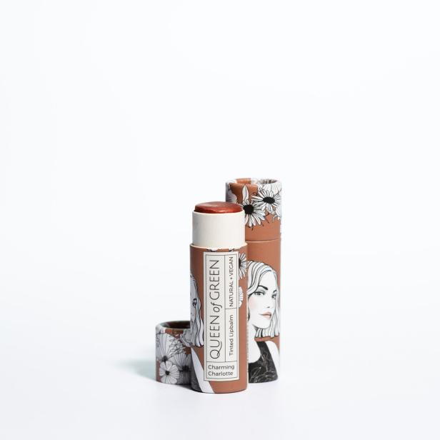 Brauner Lippenbalsam mit gezeichneter Frauenfigur und Blumenmuster auf der Verpackung, daneben der passende Deckel.