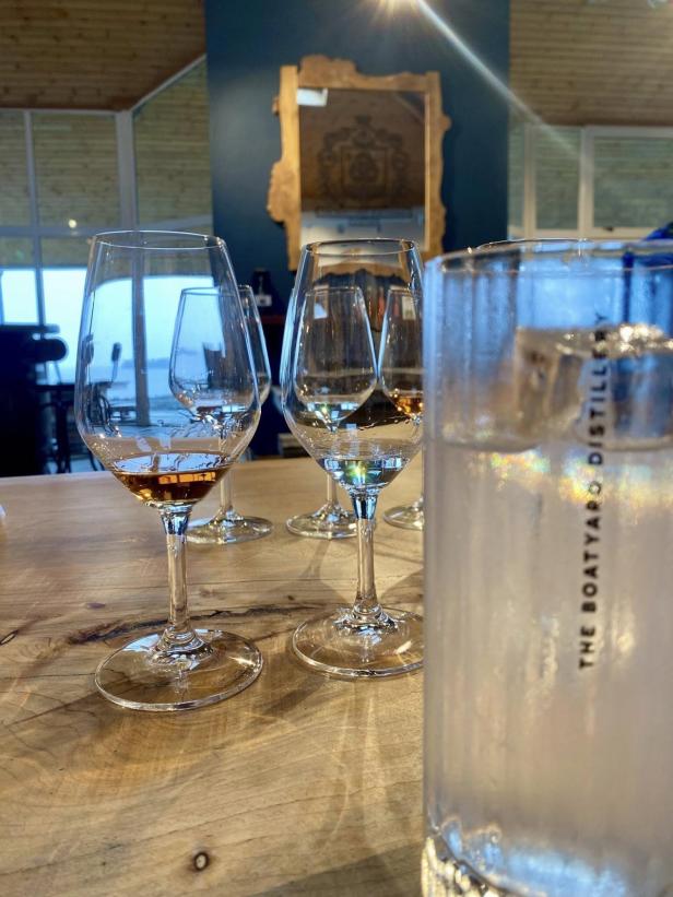 Mehrere Gläser mit verschiedenen Spirituosen stehen auf einem Holztisch in der Boatyard Distillery am Lough Erne.