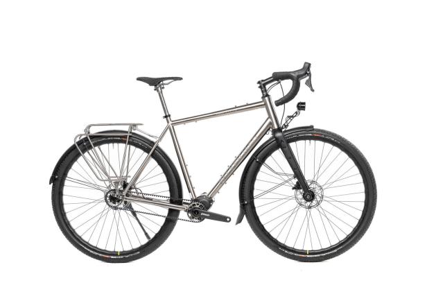 Silbernes Trekkingrad mit Gepäckträger, Schutzblechen, Rennlenker und breiten Reifen.