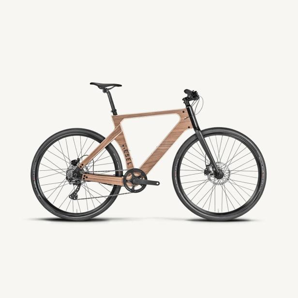 Fahrrad mit auffälligem Holzrahmen, schwarzen Reifen und geradem Lenker auf hellem Hintergrund.