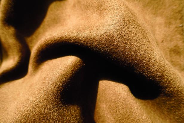 Closeup of chocolate brown faux suede polyester fabric in  soft folds