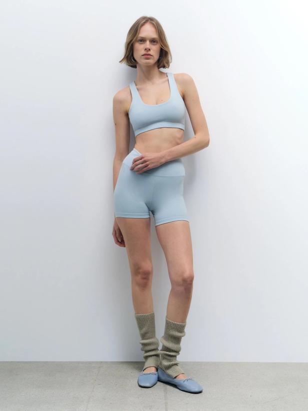 Frau in hellblauen Sport Bh und Radlerhosen mit Ballerinas und Wollstulpen