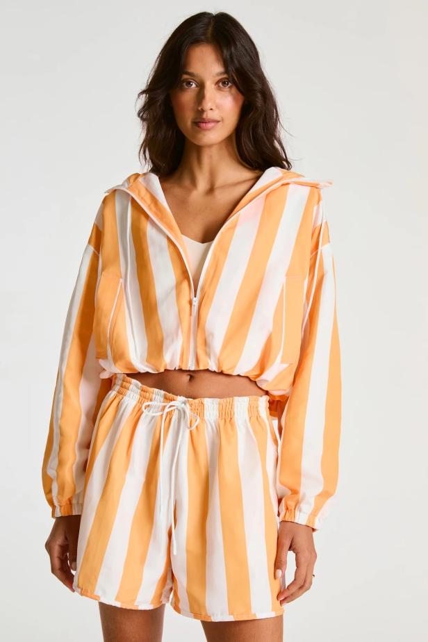 Model in Sportkleidung, orangeweiß gestreifte Jacke und Hose