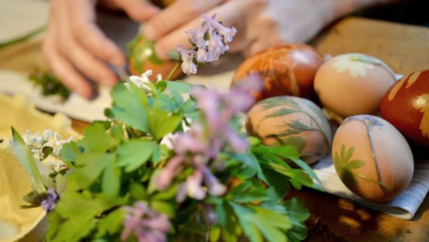 Bunte Ostereier mit Pflanzenmotiven werden verziert.