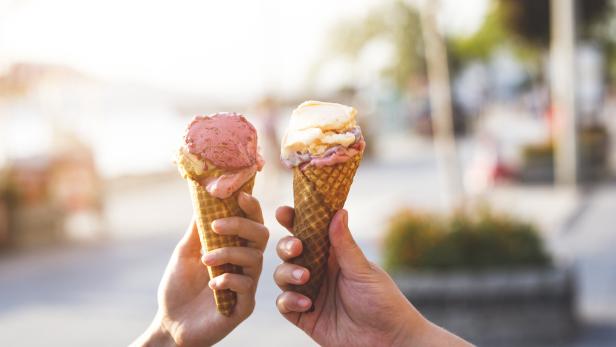 Zwei Hände halten je eine Waffel mit Eis in verschiedenen Geschmacksrichtungen.