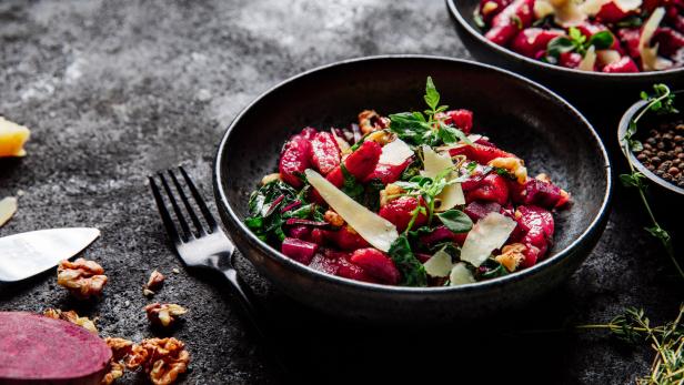 Rote Gnocchi mit Käse und Nüssen in einer Schüssel.