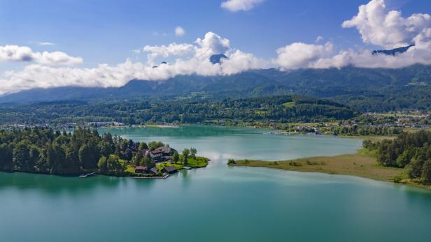 Blick auf den Faaker See mit Insel in der Mitte. Dahinter die Karawanken und der Mittagskogel