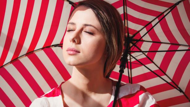 Portrait of a young woman in striped jacket and umbrella.