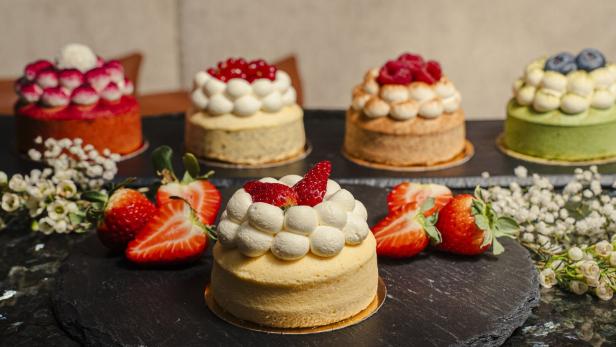 Kleine Törtchen mit Früchten und Creme stehen auf einer dunklen Platte.