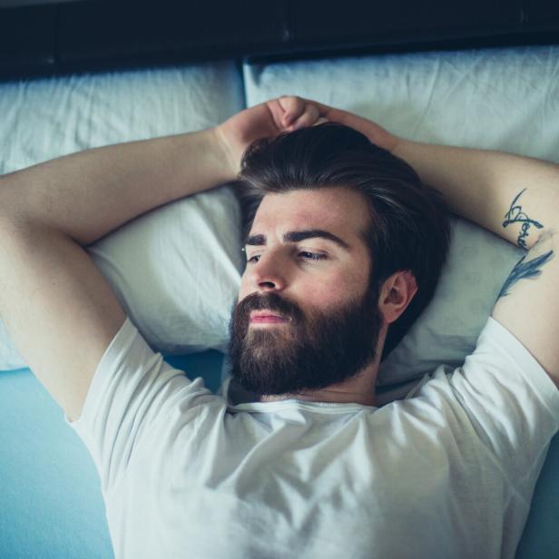 Portrait of sad bearded man lying down in the bad Nachdenklicher Mann liegt im Bett.
