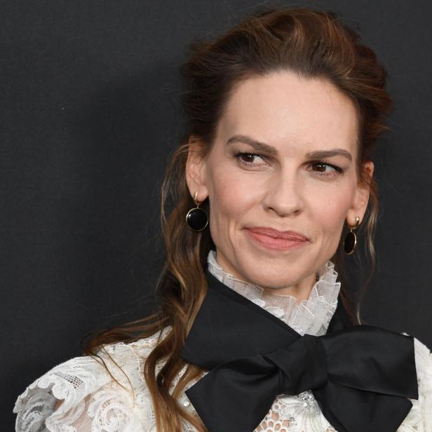 Hilary Swank mit einem weißen Spitzenoberteil und einer schwarzen Schleife.