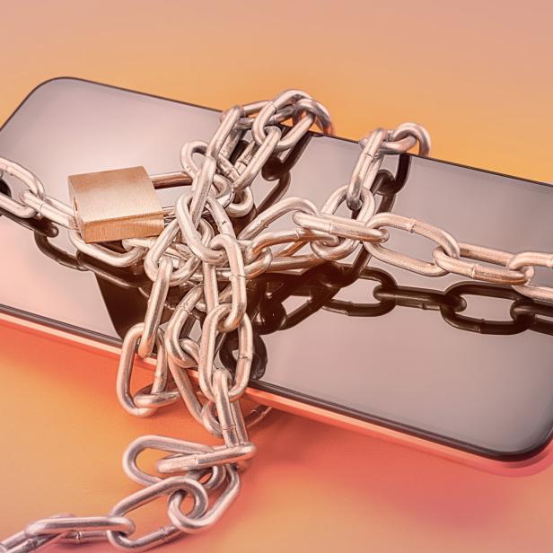 Ein Smartphone ist mit einer Kette und einem Vorhängeschloss gesichert.