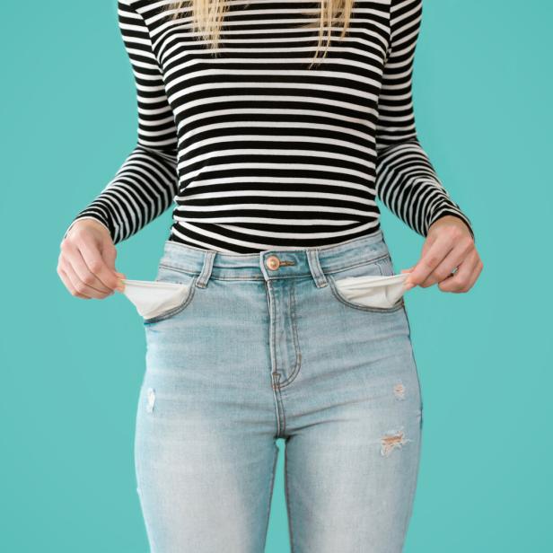 Junge Frau zeigt, dass sie keine finanzielle Reserven in ihren Hosentaschen hat.