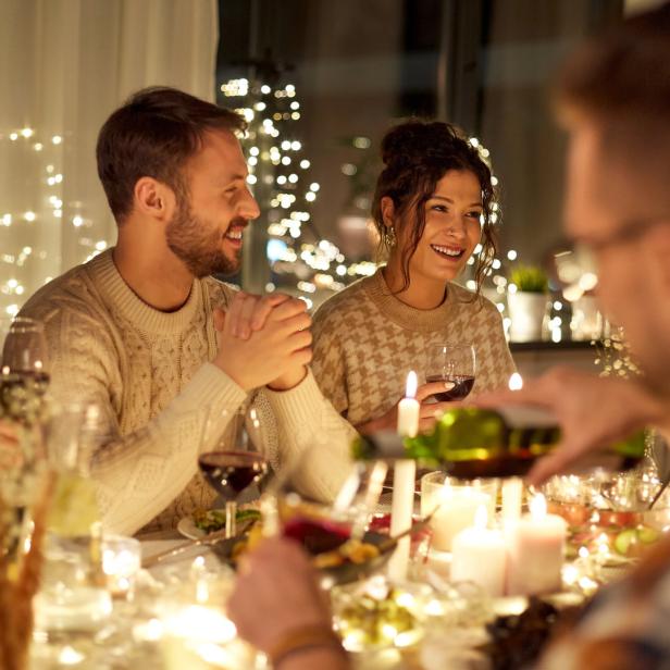 veganes Weihnachtsessen, Kerzenschein, Familie am Esstisch, Rotwein, Tischdeko