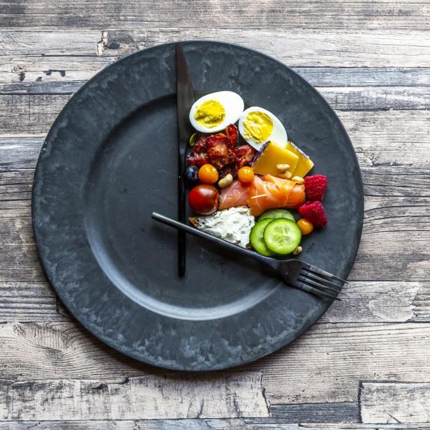 Variety of food on round plate, intermittent fasting - Stock-Fotografie