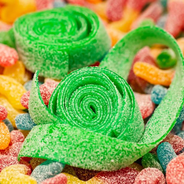 Nahaufnahme, Hintergrund mit grün gerollten Gummis, die mit Zucker überzogen sind. - Stock-Fotografie