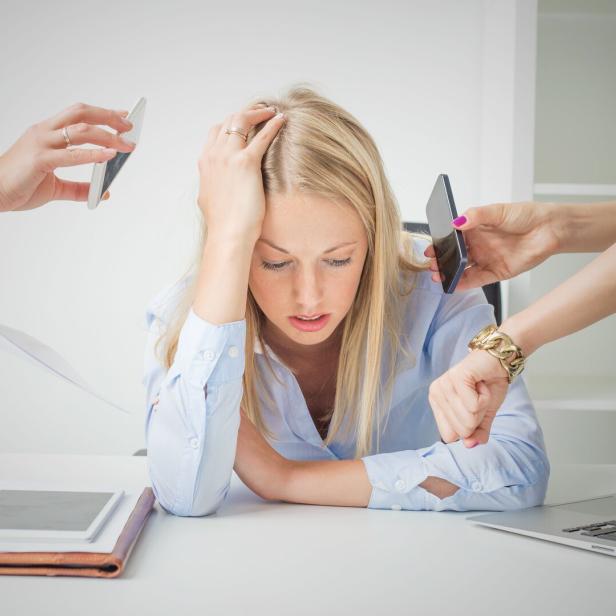 Junge Frau sitzt nach dem Urlaub wieder im Büro und ist gestresst.