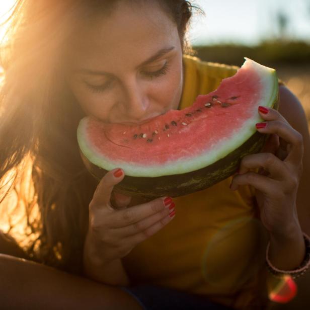 Junge Frau isst Wassermelone im Freien - Stock-Fotografie