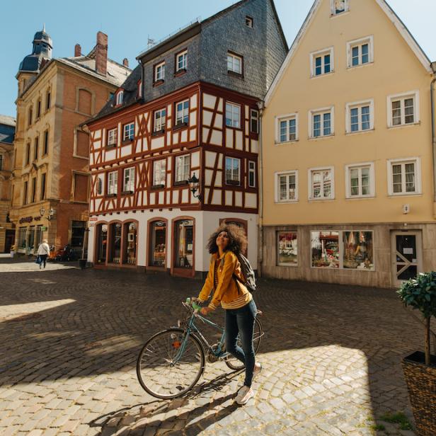Mainz: Junge Frau mit Fahrrad bewundert Mainzer Altstadt, Fachwerk im Hintergrund