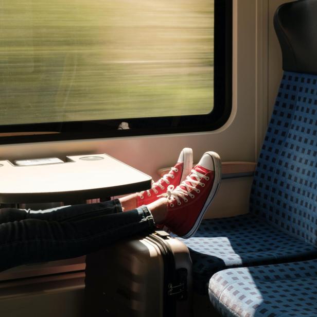 Füße mit Schuhen und ein Koffer in der Deutschen Bahn