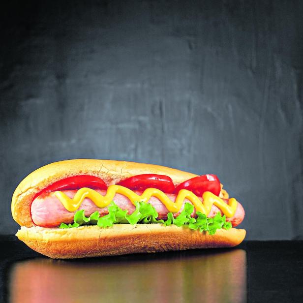 Big hotdog with sausage tomatoes, mustard and salad isolated