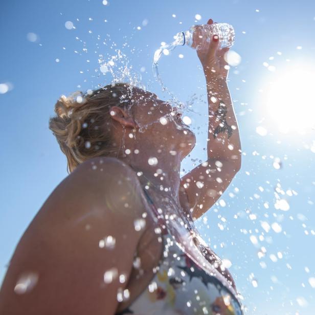 A young woman cools down with cold water during the summer heat. - Stock-Fotografie