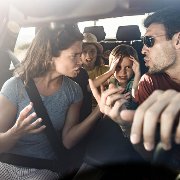 Eltern streiten im Auto, Kinder sitzen auf der Rückbank und halten sich die Ohren zu, Krise im Urlaub