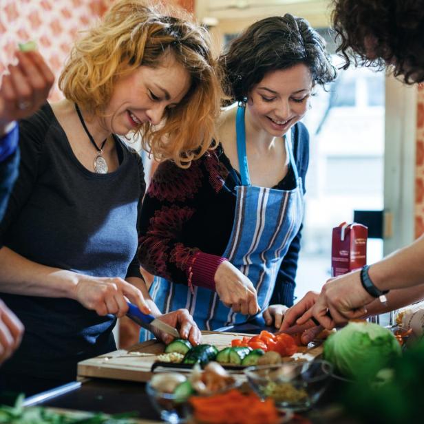 Cooking class participants enjoy cutting vegetable - Stock-Fotografie