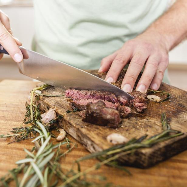 Cutting steak on chopping board - Stock-Fotografie