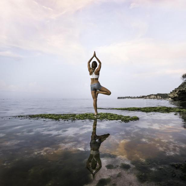 Frau praktiziert Yoga am See