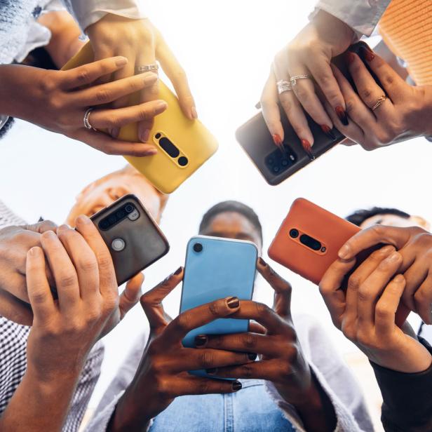 Jugendliche stehen im Kreis und halten Smartphones in der Hand