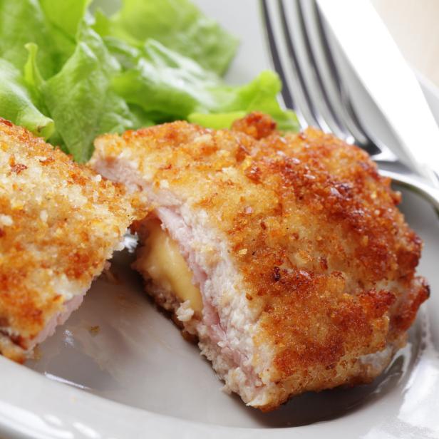Cordon bleu mit schmelzendem Käse und Schinken auf einem Teller mit Salat